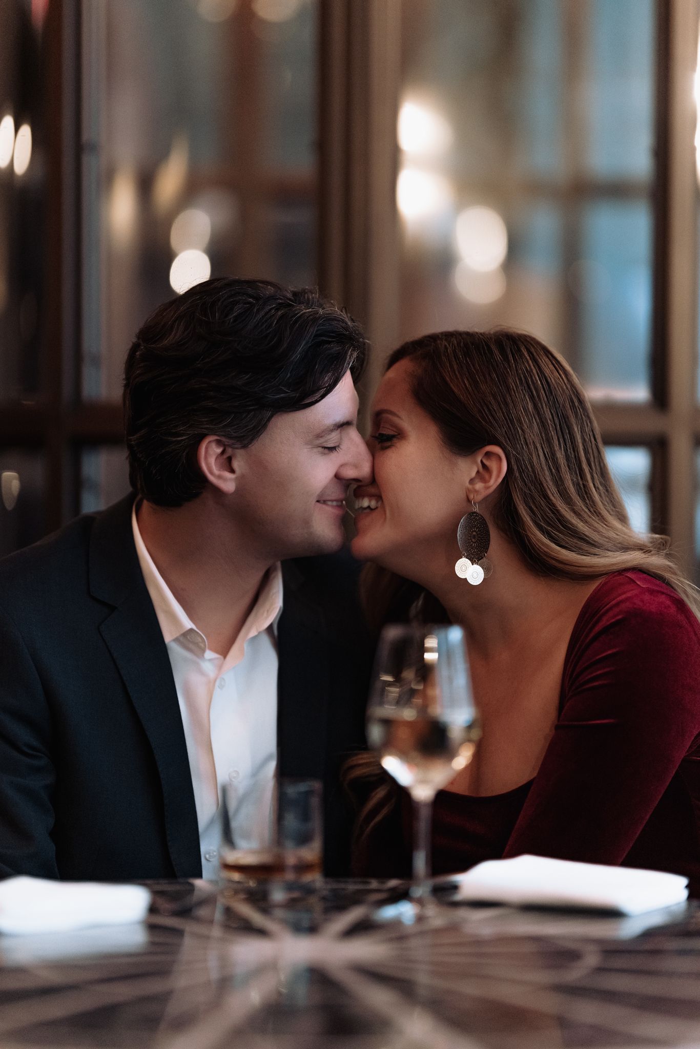 An intimate restaurant moment between a couple in formal attire sharing a close conversation.