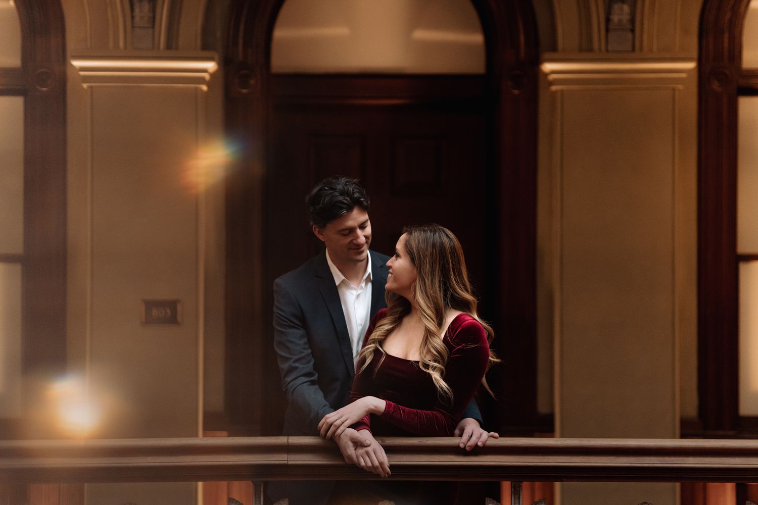 A romantic couple shares an intimate moment in an elegant architectural setting.