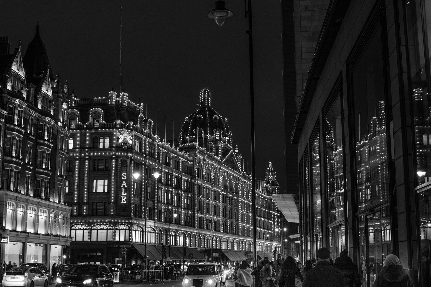 Historic Harrods department store illuminated at night in black and white.
