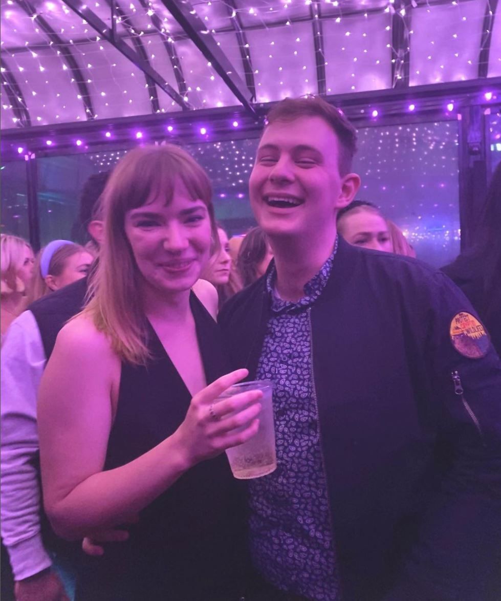 Daniel Bowler, photographer, and partner, smile and laugh to camera in a sweet, intimate moment at a NYE event.