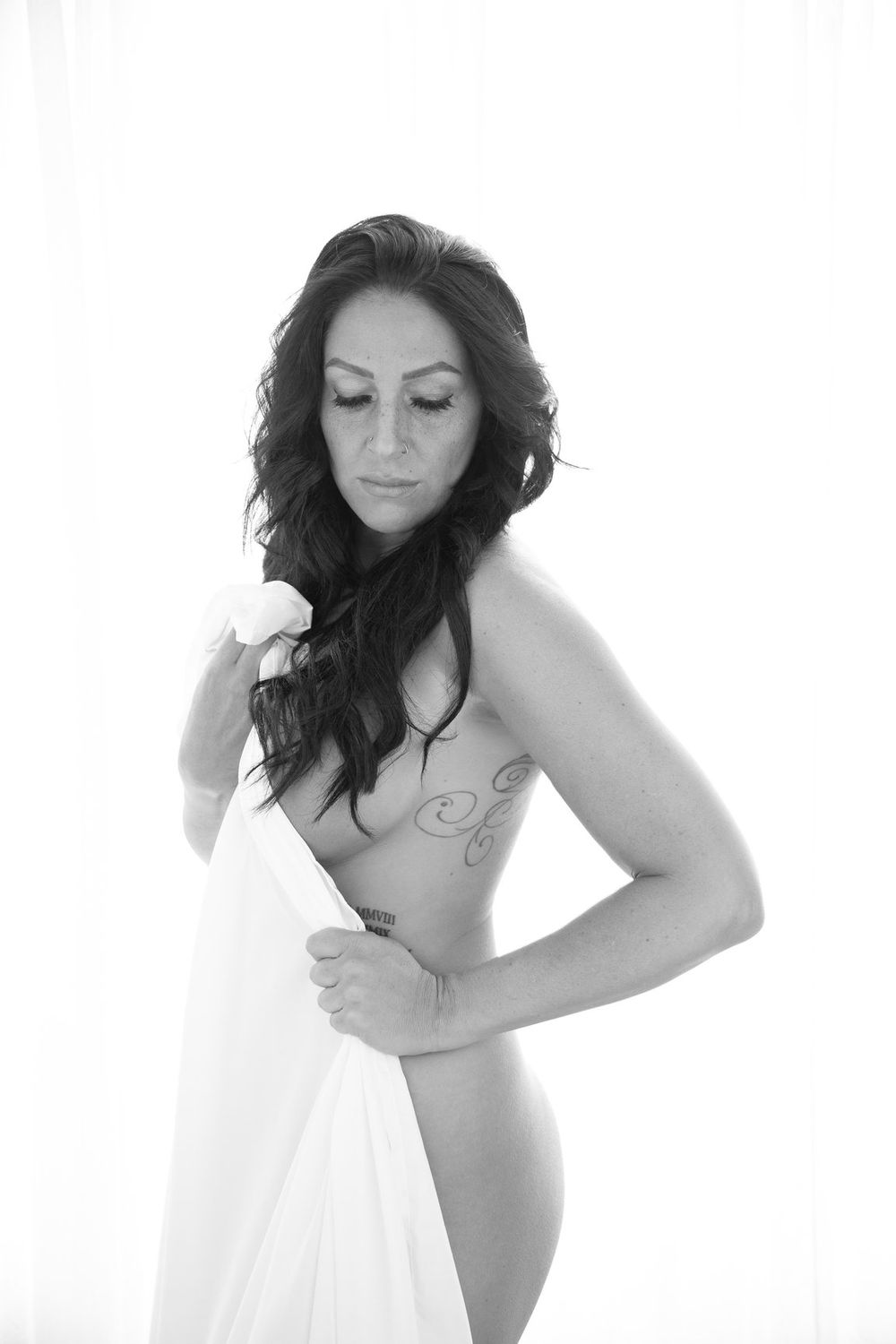Artistic black and white boudoir portrait with draped white fabric.