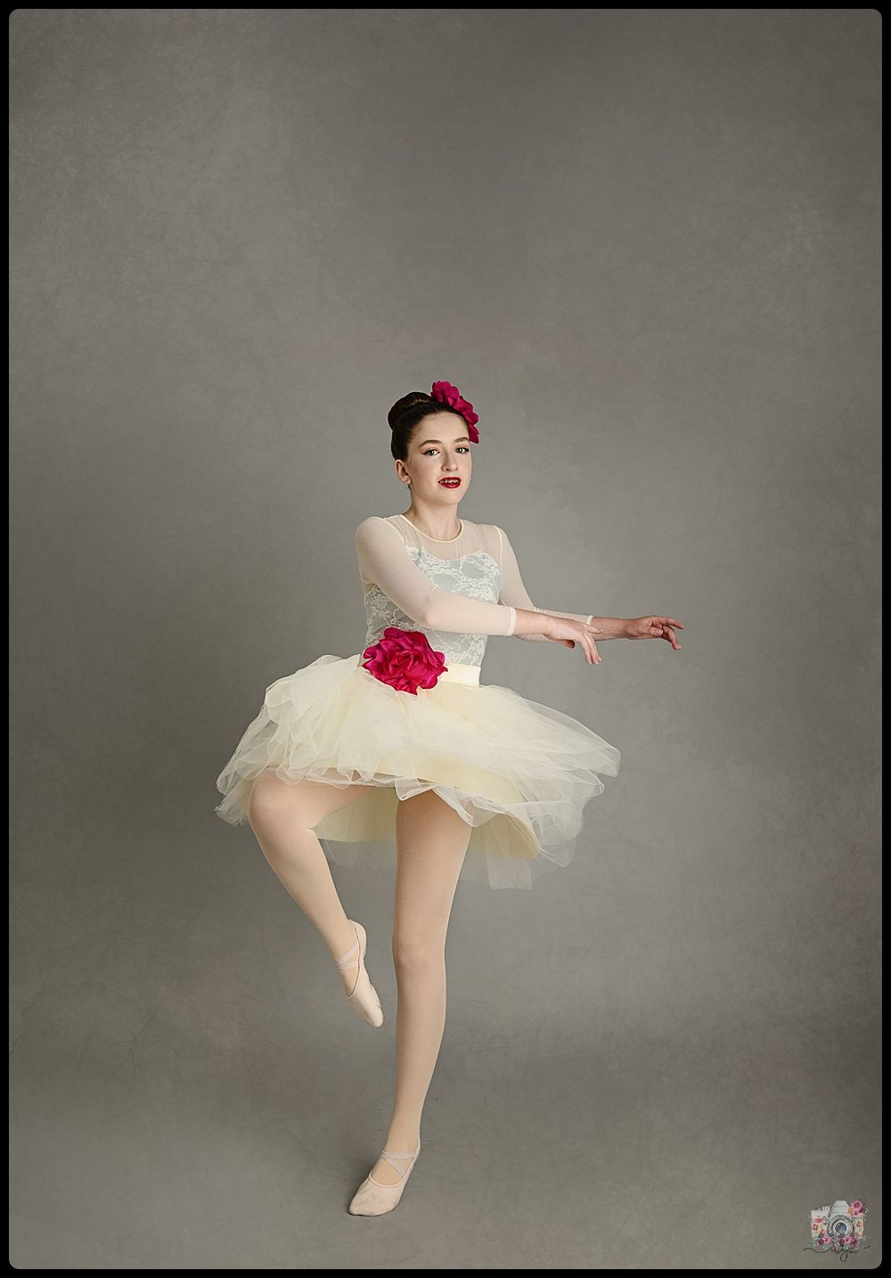A ballerina in a white tutu with red accents twirls elegantly against a gray background.