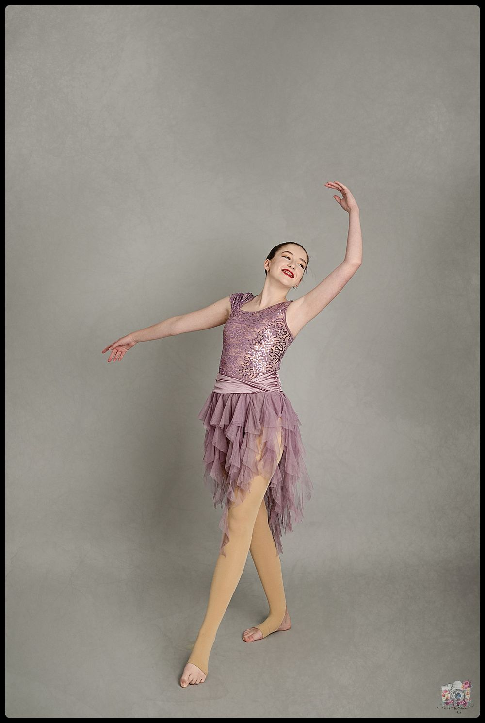 Dancer in lavender sequined costume with flowing skirt performs graceful pose.