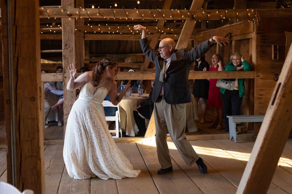 Dancing and celebration inside rustic wooden barn with string lights.