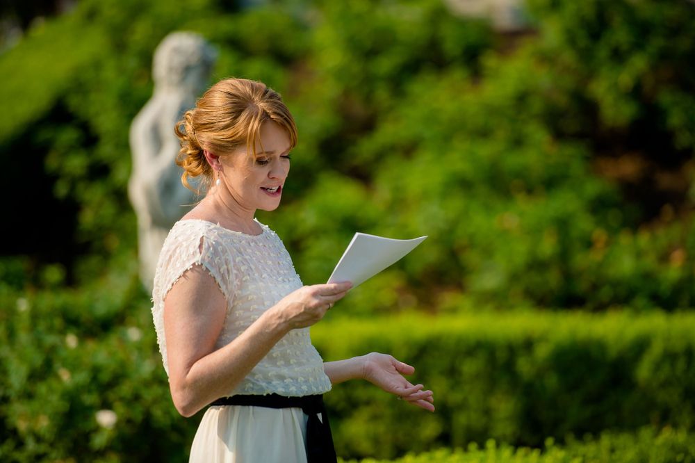 Person reading from paper during outdoor garden ceremony.Commodore Perry Estate Wedding