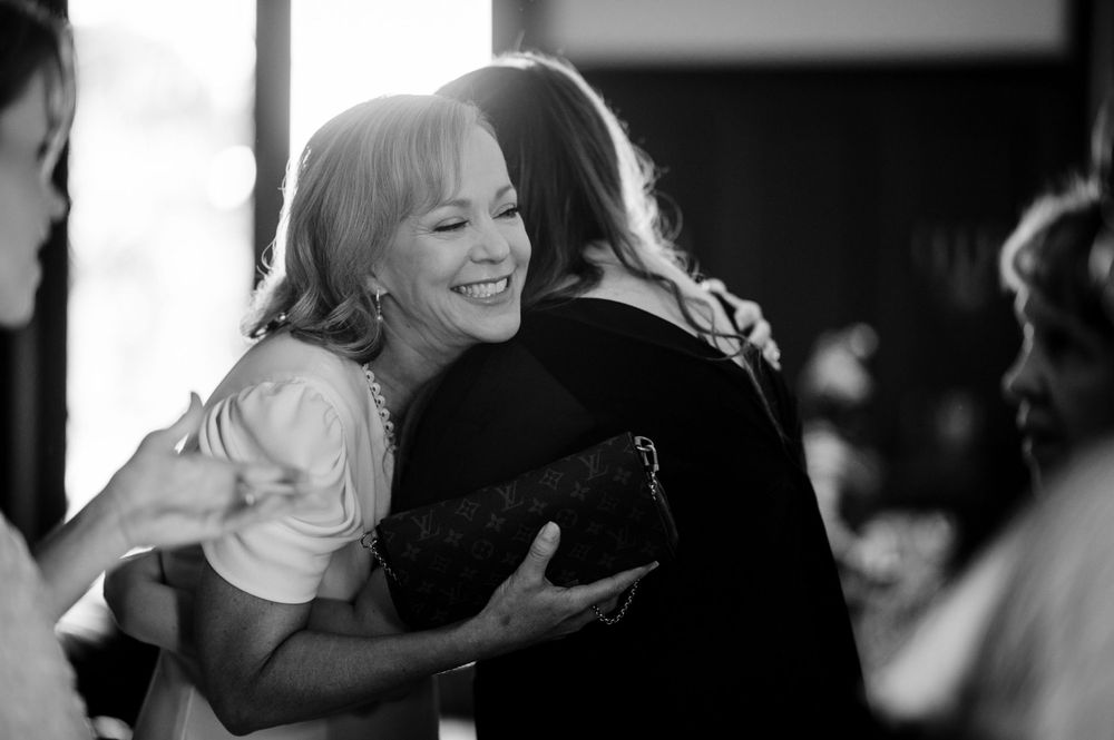 A candid black and white photo capturing a joyful embrace at an indoor event.Commodore Perry Estate Wedding