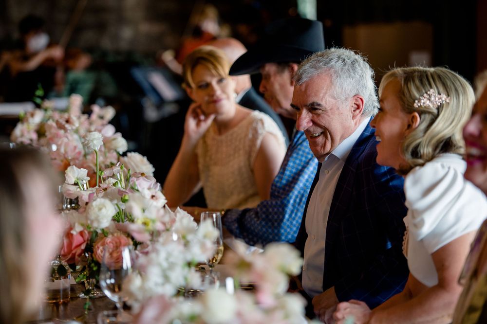 Reception table decorated with elegant floral arrangements as guests share laughter.Commodore Perry Estate Wedding