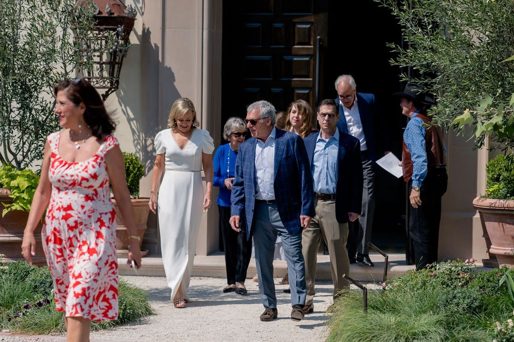 A group of people walking out of a building entrance on a sunny day.Commodore Perry Estate Wedding