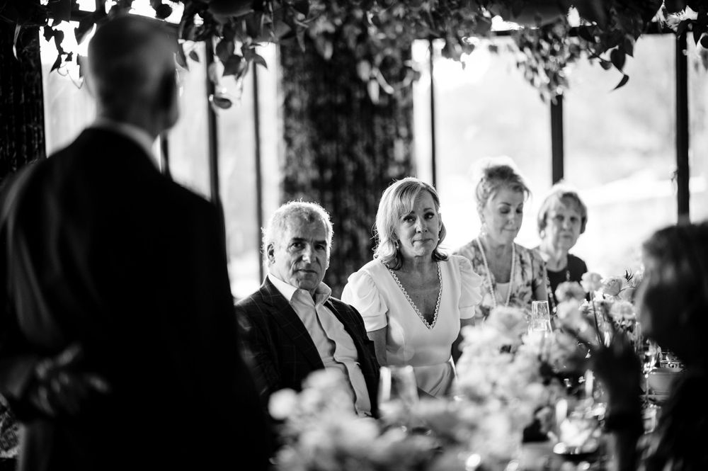 A candid black and white photo of guests during a wedding speech.Commodore Perry Estate Wedding