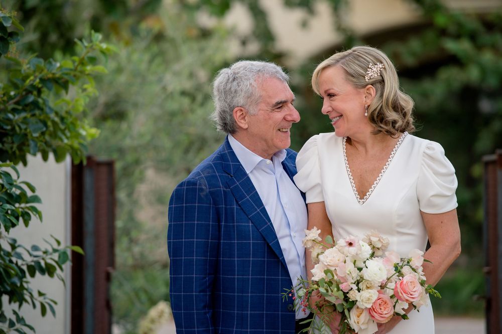A sweet moment between a couple in formal wear holding a bouquet in a garden setting.Commodore Perry Estate Wedding