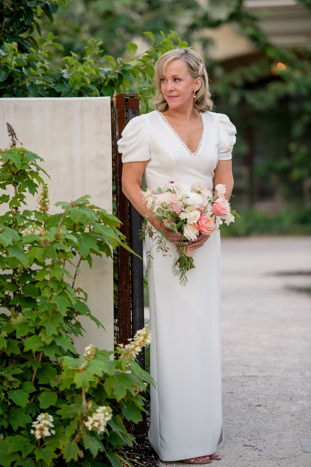 Bride in white dress with puff sleeves holds romantic bouquet of pink and white flowers in garden setting.Commodore Perry Estate Wedding