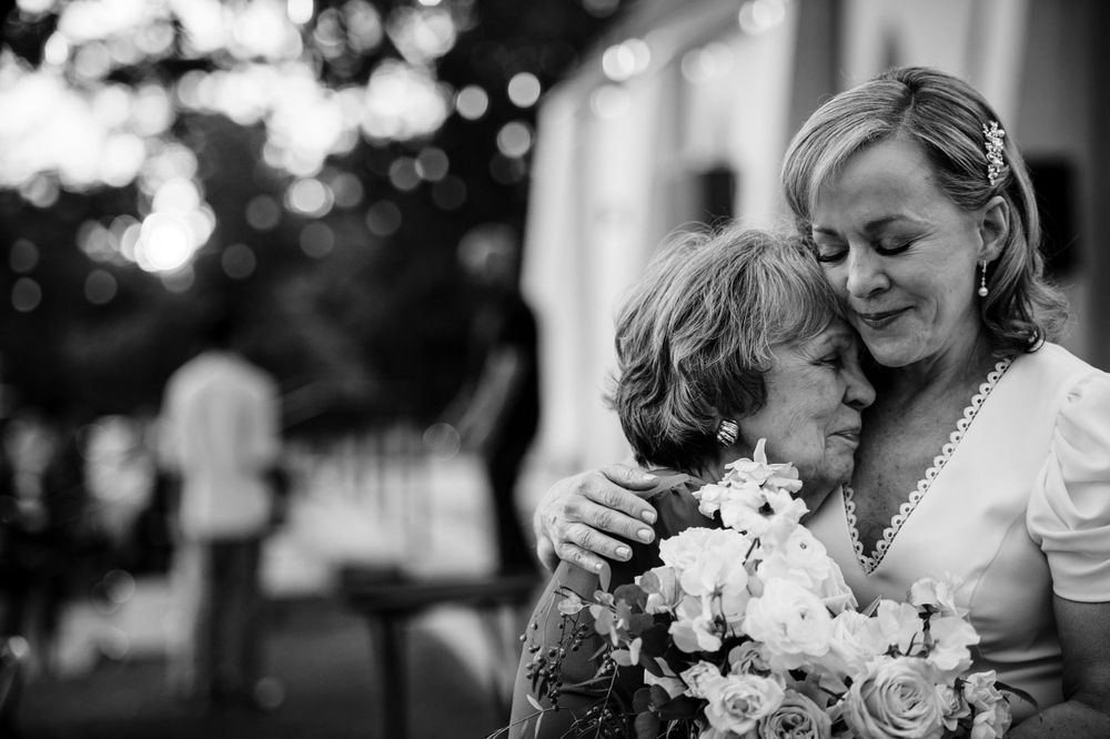 Intimate black and white moment captured between two people embracing with flower bouquet.Commodore Perry Estate Wedding