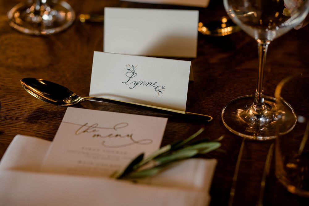 Wedding place setting with elegant name card, silverware and wine glass on wooden table.Commodore Perry Estate Wedding