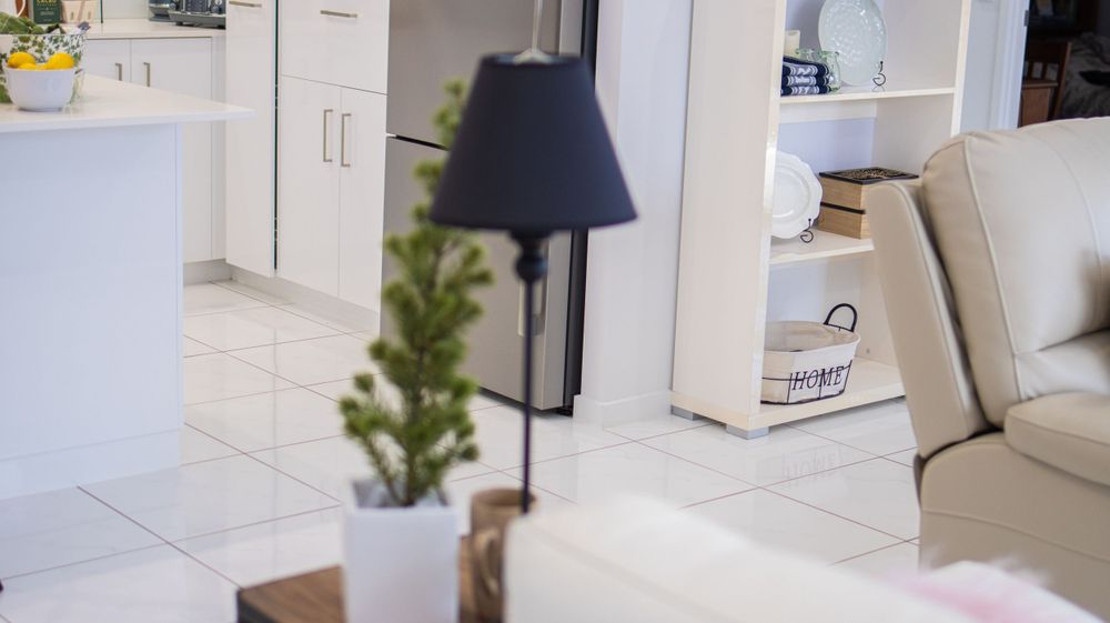 Modern white interior with a floor lamp, small potted plant, and white cabinetry in a minimalist setting.
