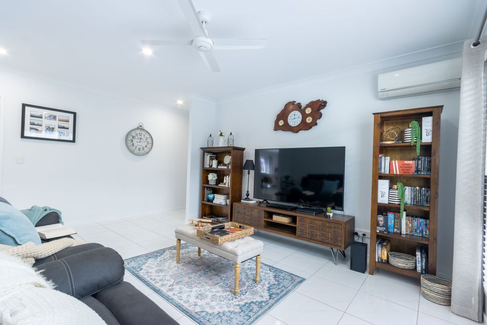 Modern living room featuring gray sectional, wooden media center and decorative bookshelves.