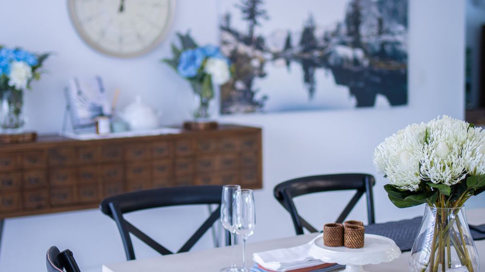 Contemporary dining setup with hydrangea centerpiece and winter lake scene artwork.