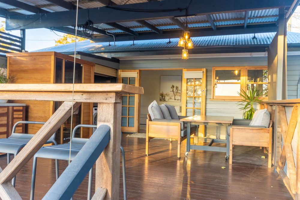 Stylish deck area with contemporary furniture and warm lighting under a metal roof structure.