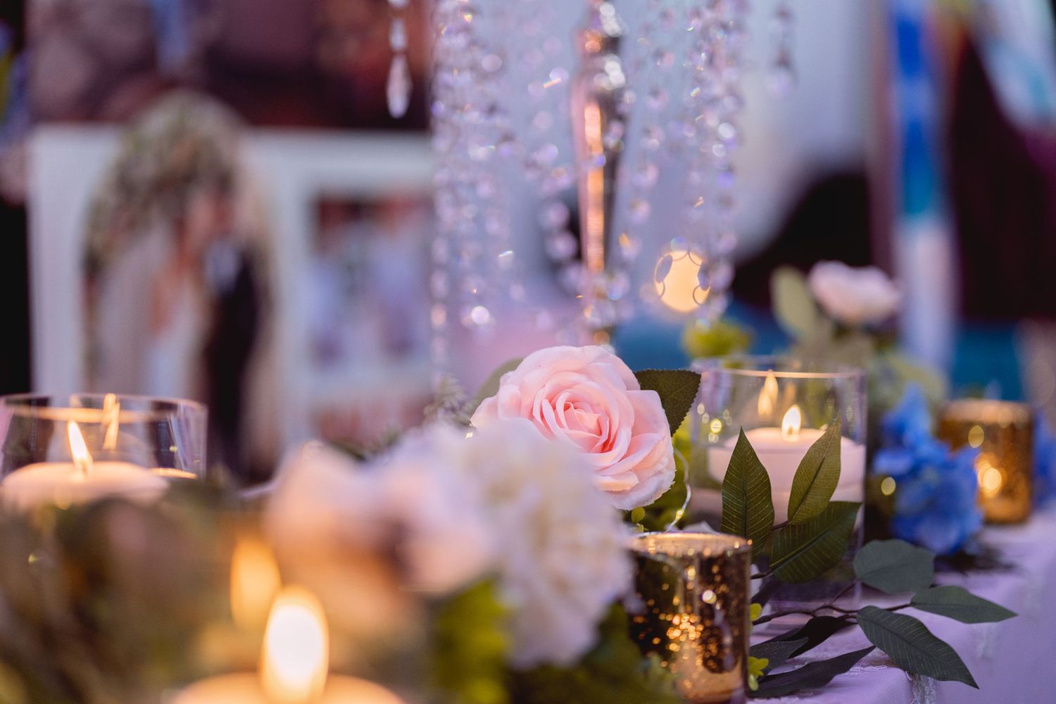 Romantic table setting with pink roses, crystal decorations and glowing candlelight.