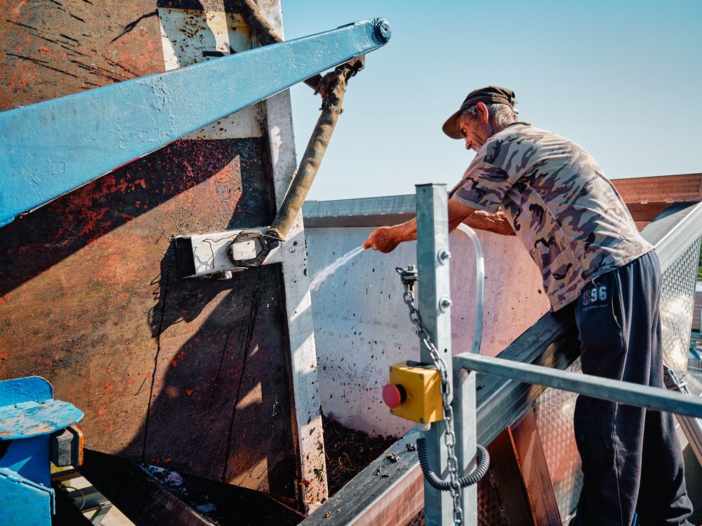 Worker operates industrial equipment on elevated platform against brick wall.