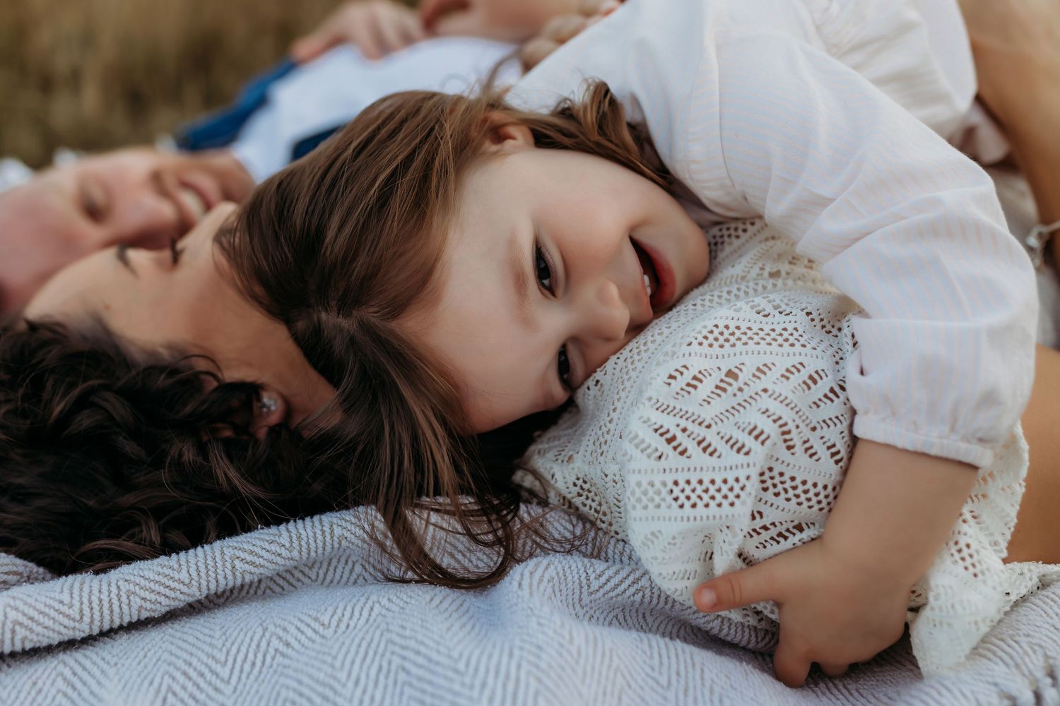 a family lying in long grass having a candid moment during a photoshoot with India Foxx photography.