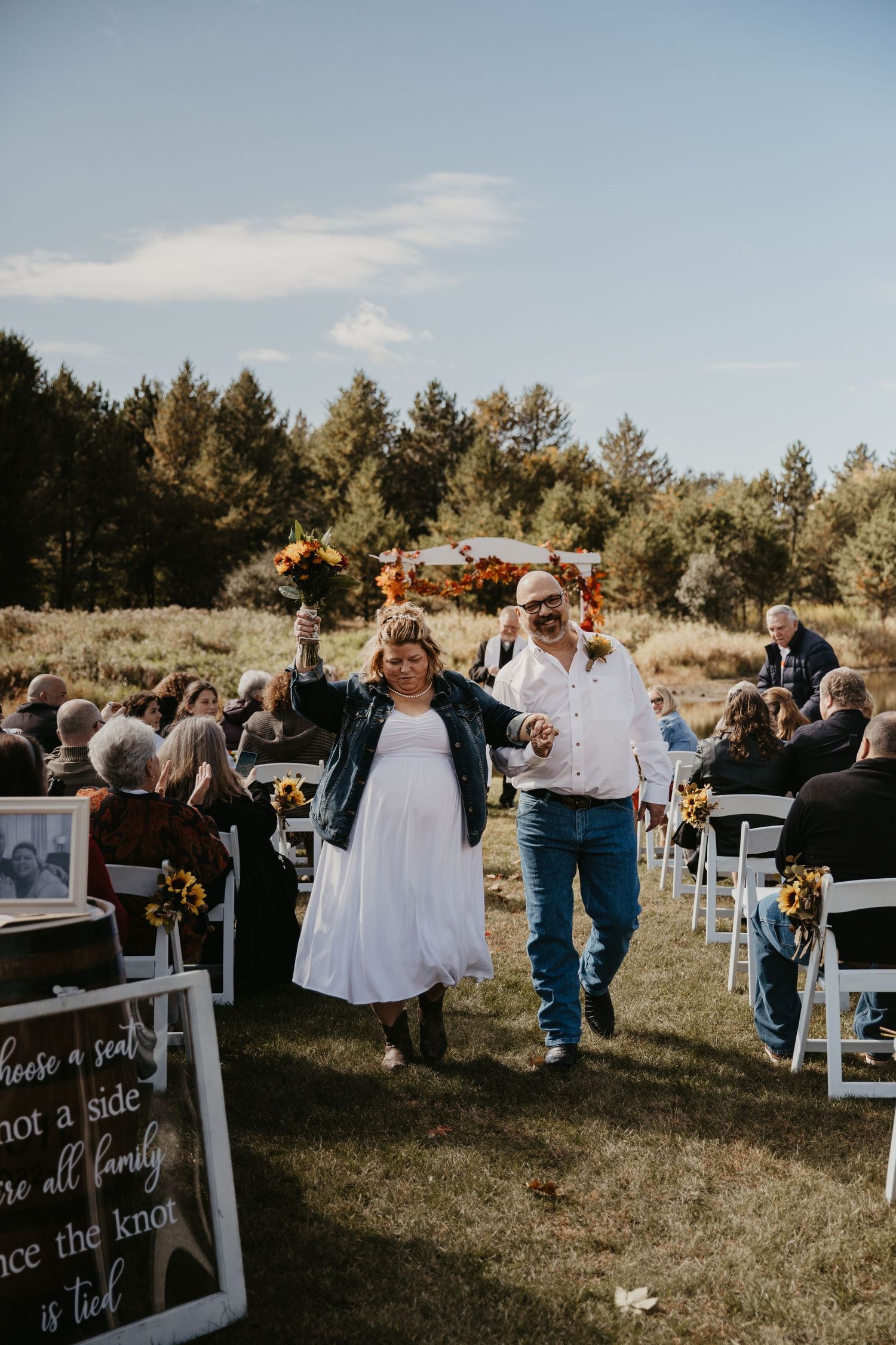happy couple walks back down the isle as husband and wife, cheering and waving arms and flowers, everyone is smiling and happy
