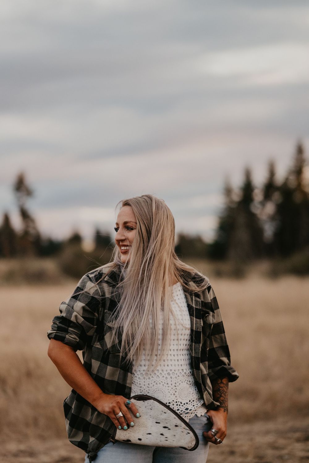 A candid outdoor portrait in a field wearing plaid and white knit on an overcast day.