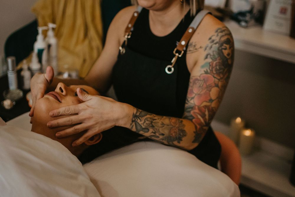 Close-up of tattooed hands performing massage therapy in a spa setting.