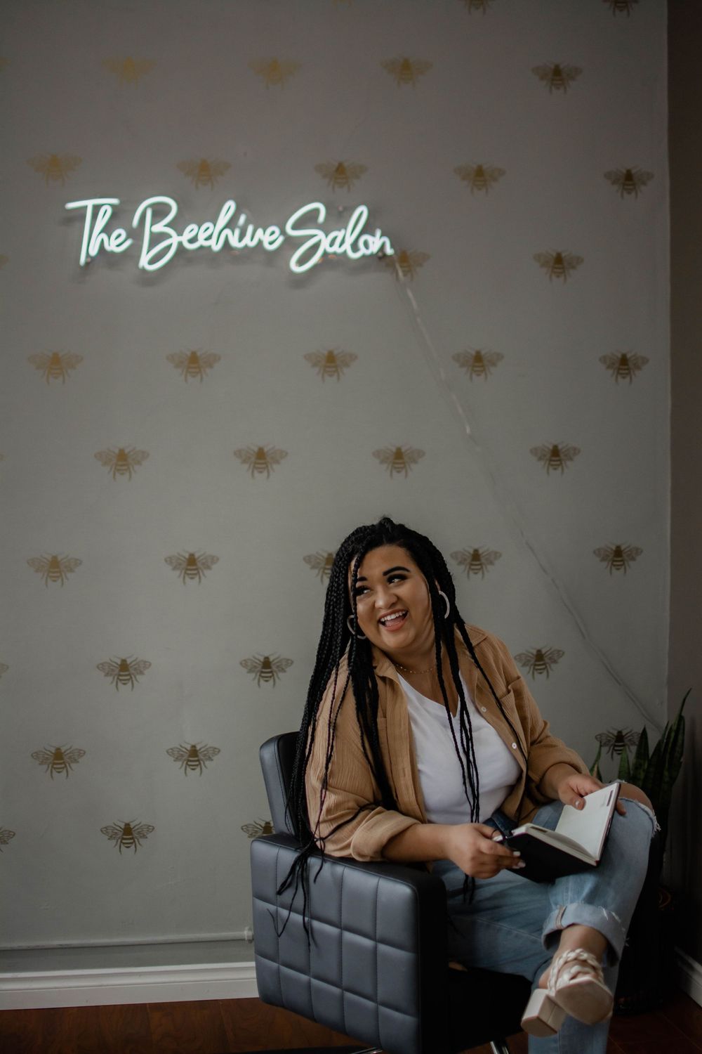 Interior of The Beehive Salon with neon signage and golden bee wallpaper pattern.