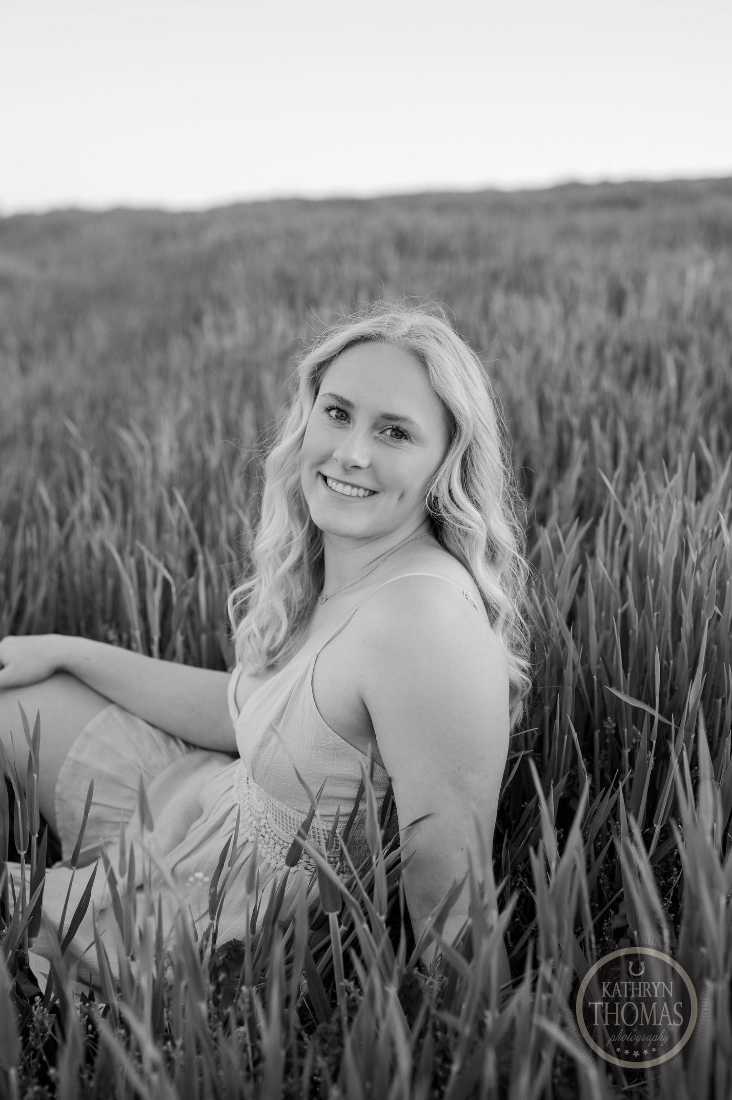 Black and white portrait taken in tall grass field with natural lighting.
