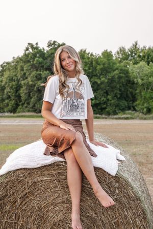 A senior portrait on a hay bail