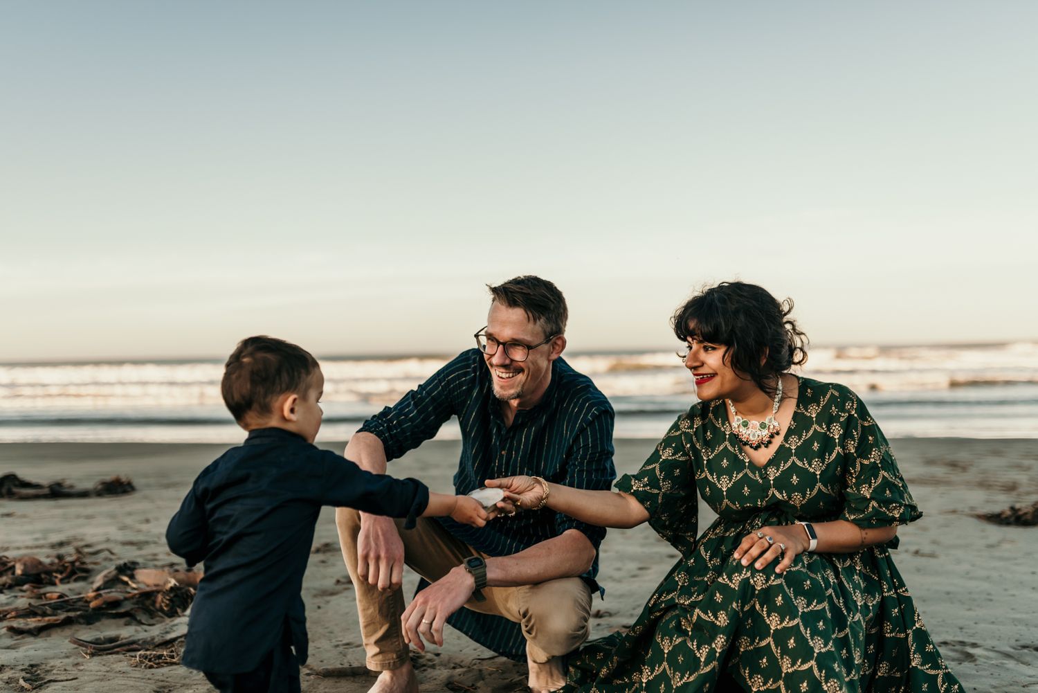 Family playing and interacting together on a beach at sunset.