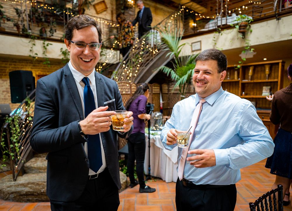 Two people enjoying drinks at festive indoor gathering with decorative lights.