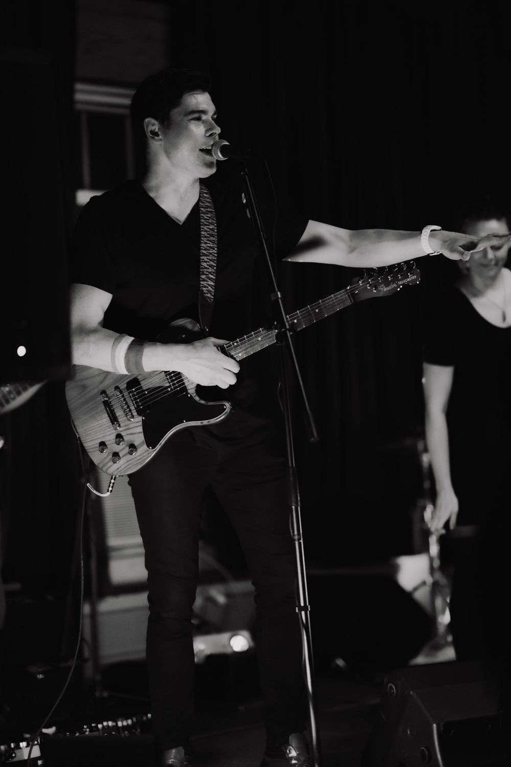 Musician performing on stage with guitar in black and white photography.
