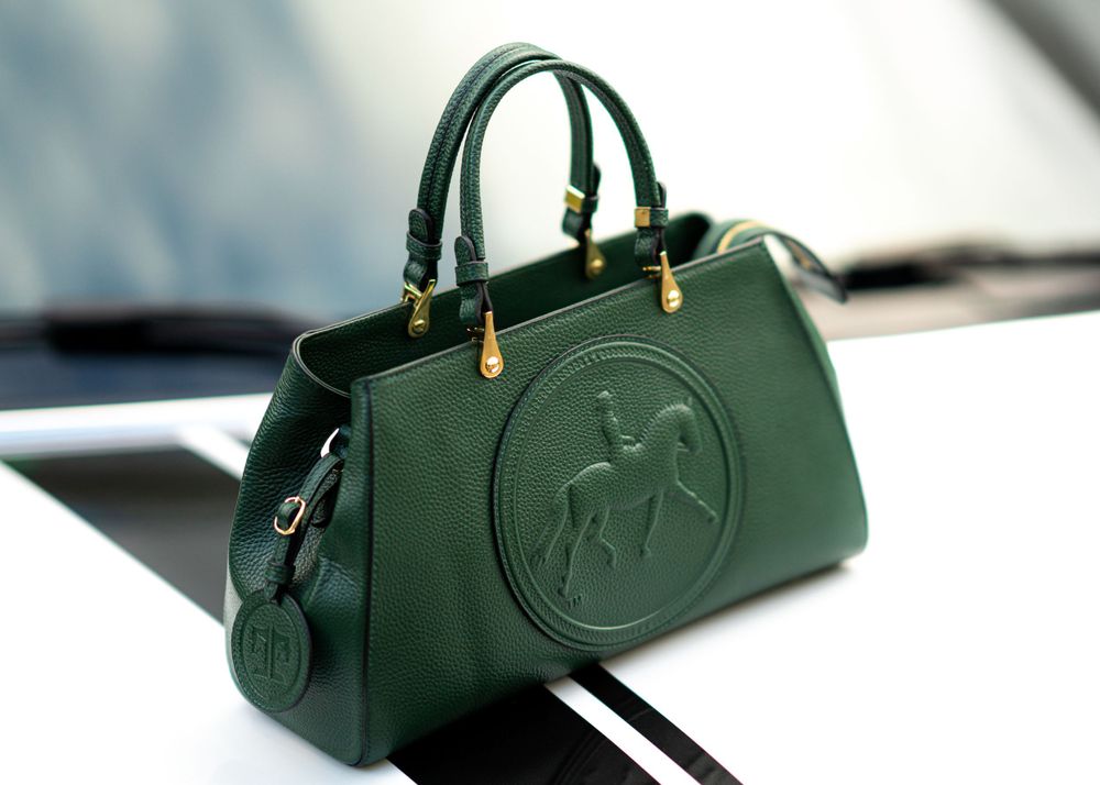 Green leather handbag with embossed horse logo and gold hardware details.