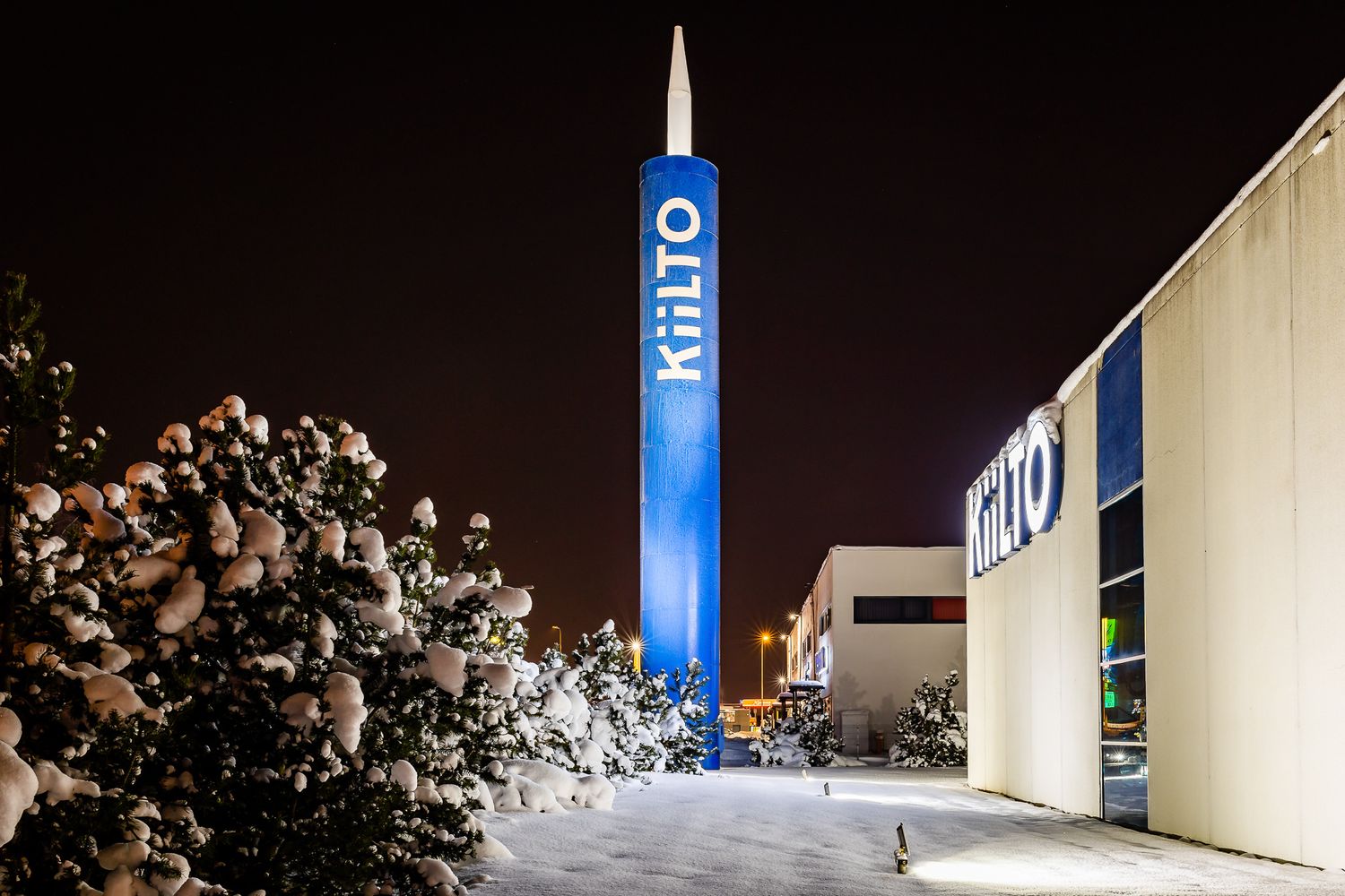 Tall blue-lit BHRD tower stands illuminated against dark night sky with snow on ground.