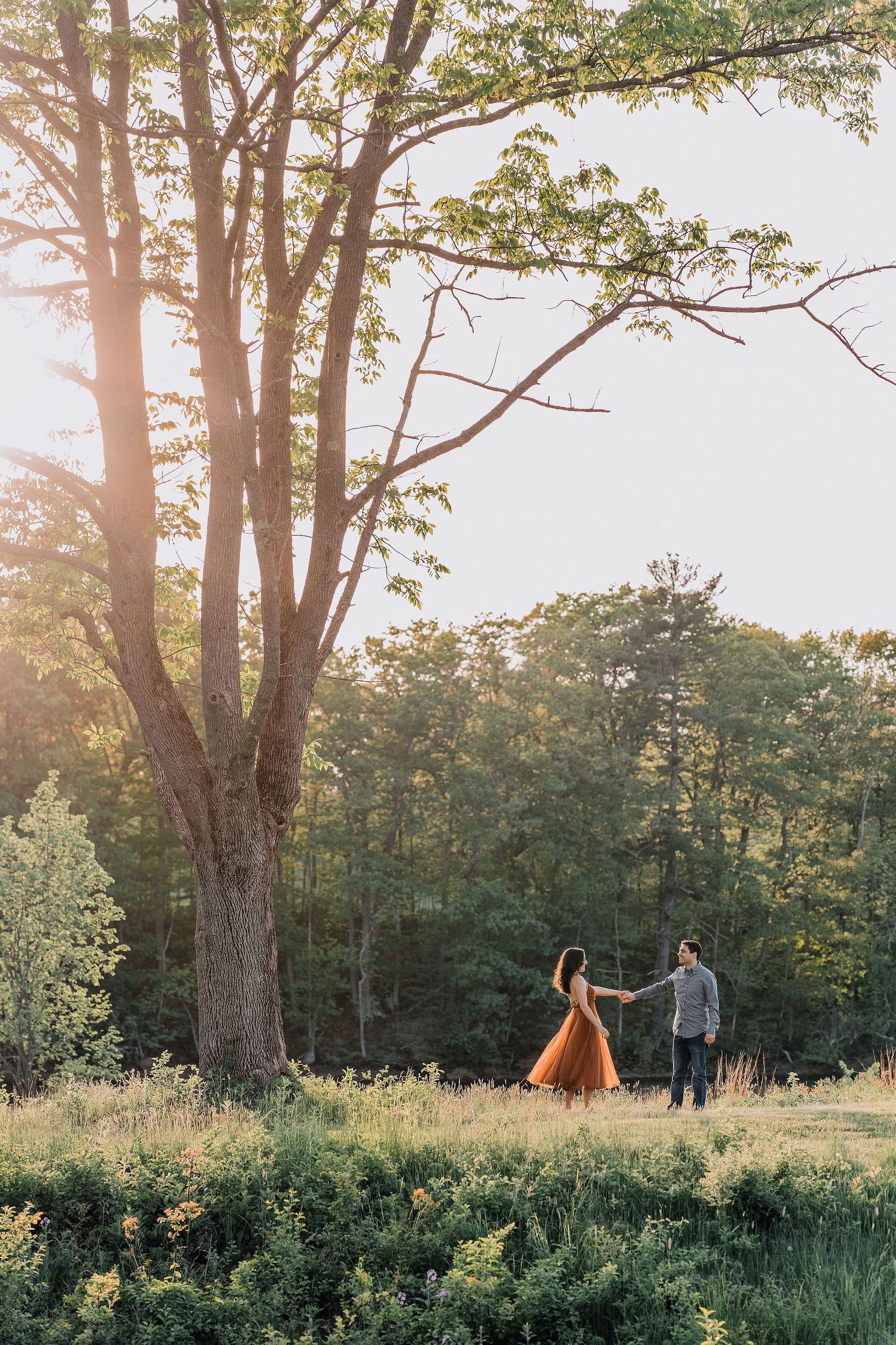 woman pulling man along by the hand in grass at southern Maine wedding venue