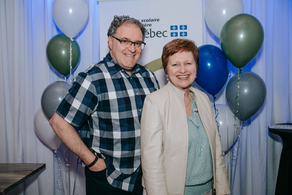 Event attendees gathering under blue and white decorations with Quebec organization signage visible.