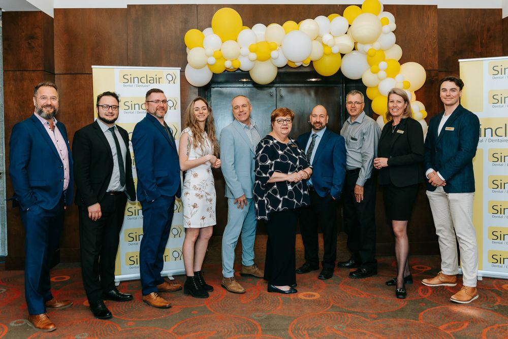 Corporate event with yellow balloon decorations and attendees gathered along a brick wall.
