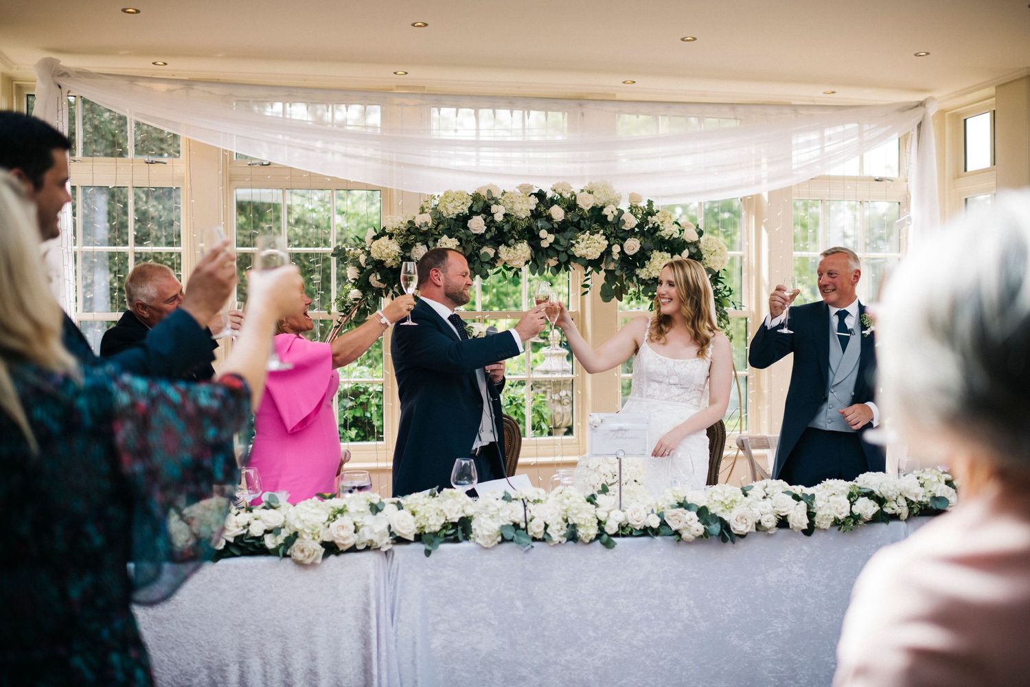 Bright and airy wedding reception venue decorated with white floral arrangements and natural lighting.