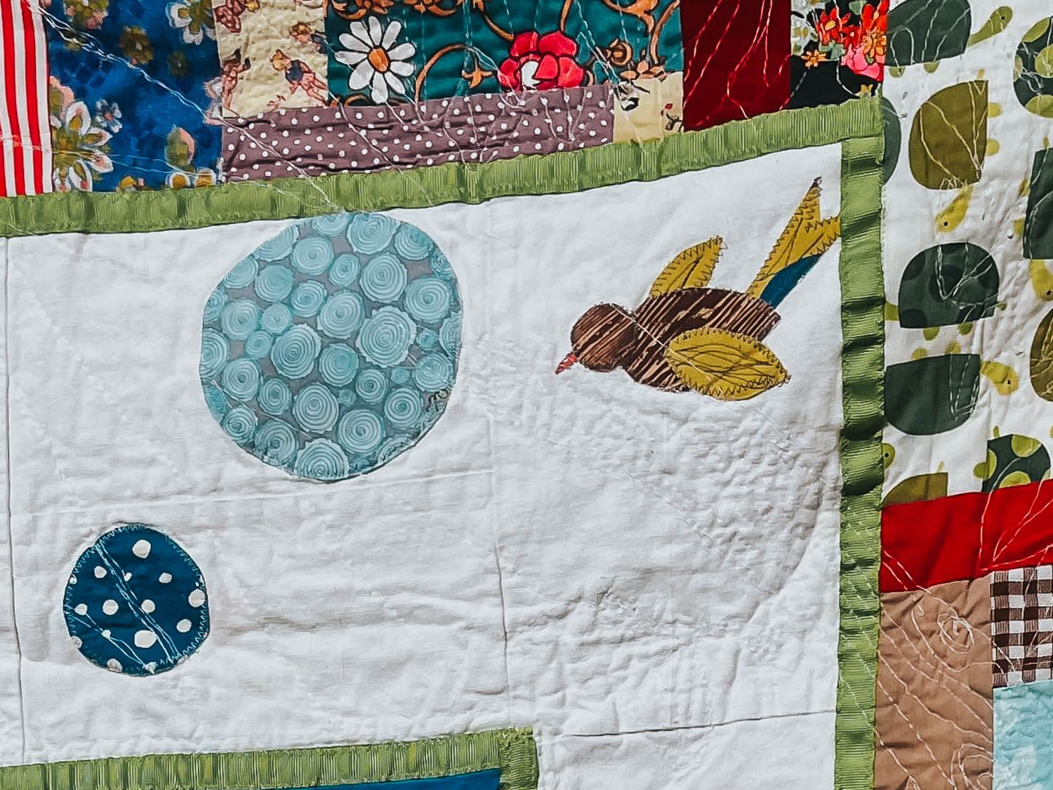 Bird applique quilted on the face of a quilt.