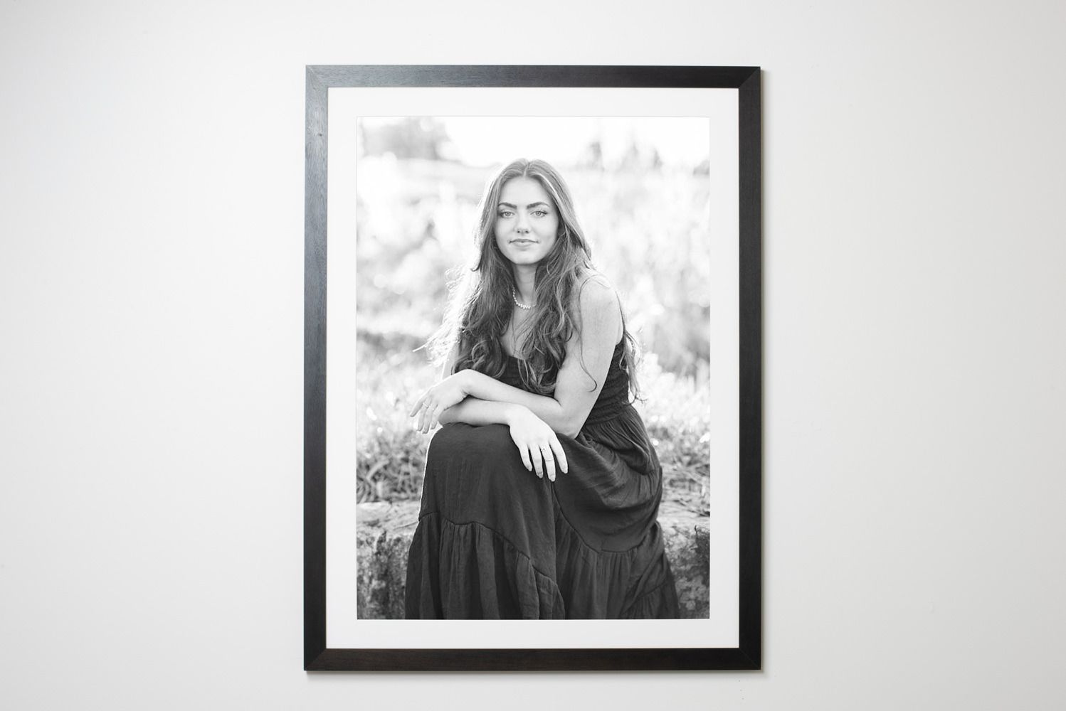 Black and white framed portrait photographs displayed on a white wall.