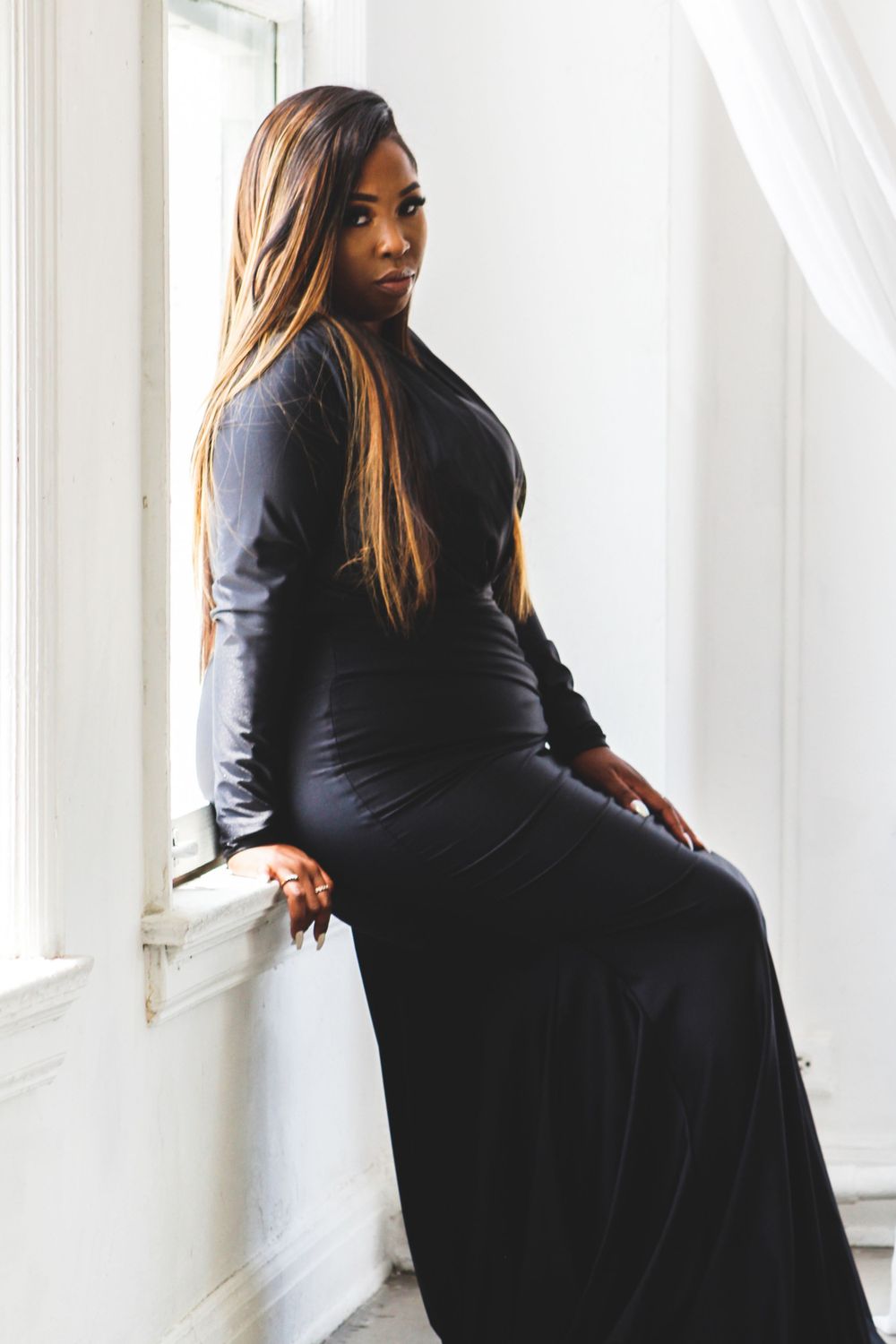 Fashion portrait in fitted black dress by bright window.