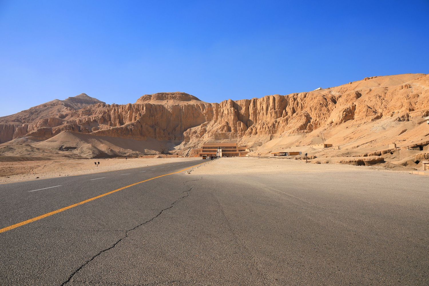 Desert highway road leading past rocky cliffs and mountains in Egypt.