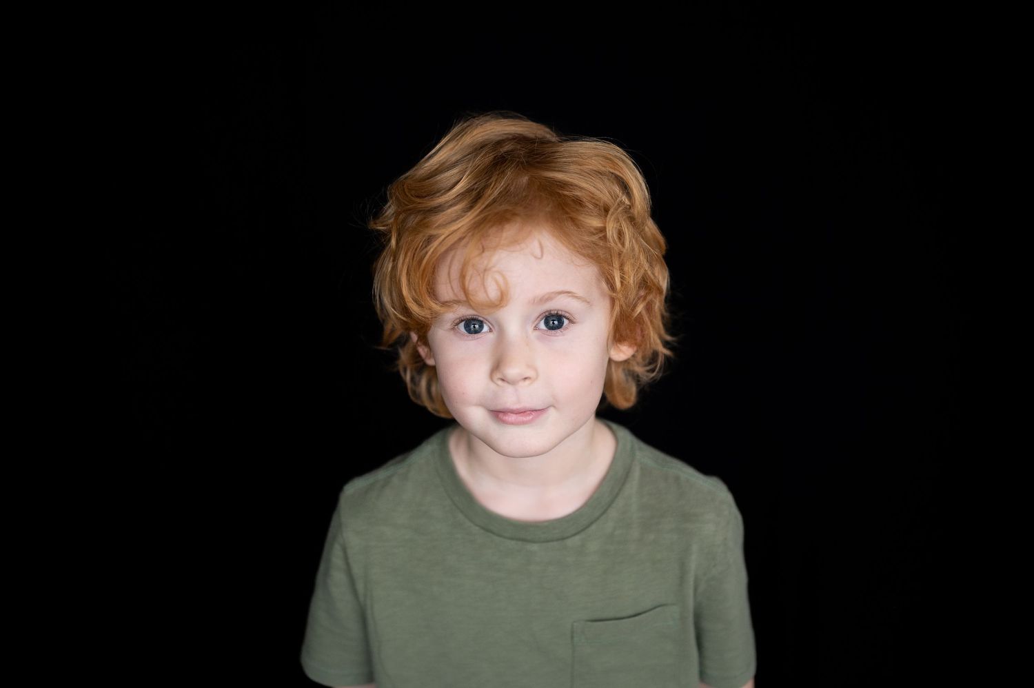 a boy with red hair smiles for a portrait