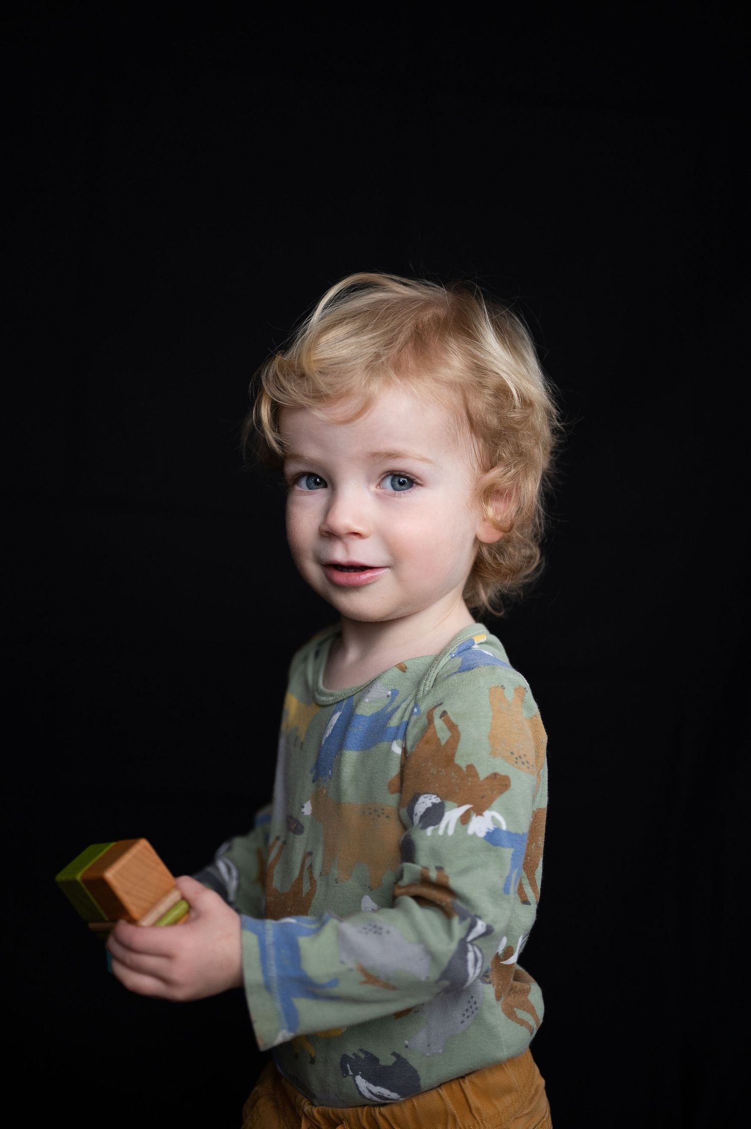 a toddler holds blocks and looks into the camera for a portrait photo