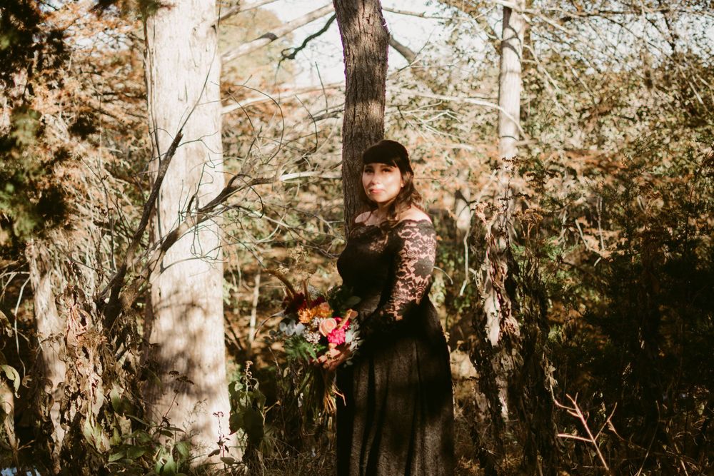 Dreamy forest portrait in black lace featuring delicate floral bouquet.