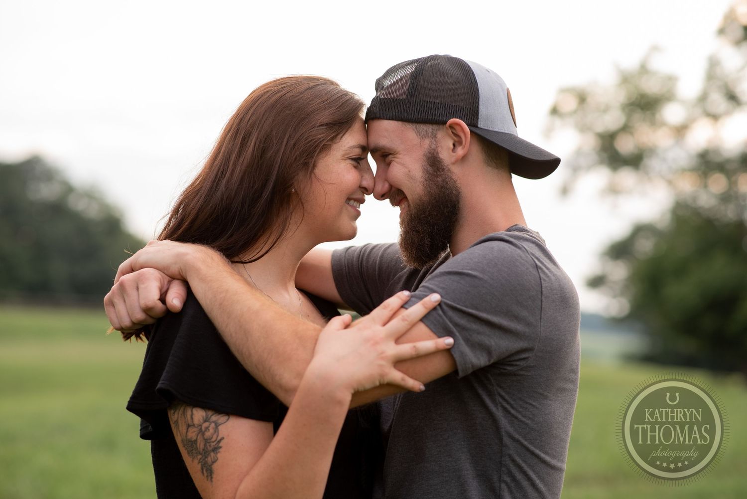 A couple shares a tender moment together in an open field.