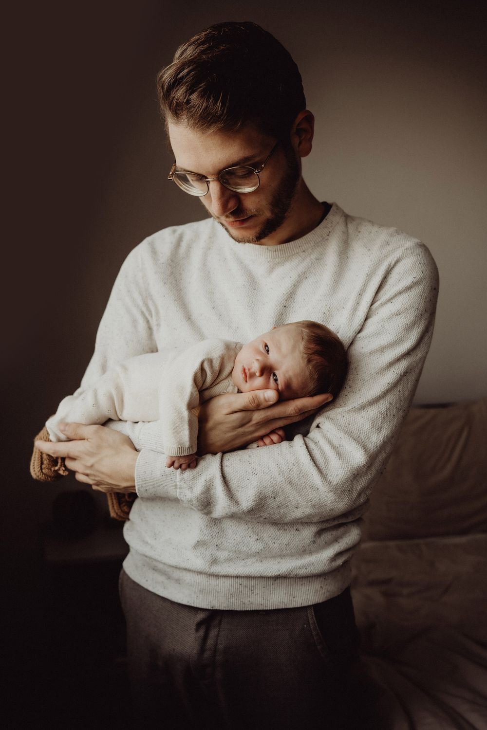 Tender moment of baby sleeping while being held in cozy white sweater.