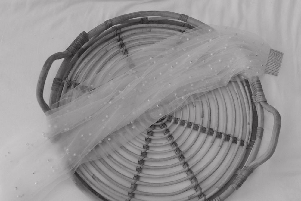 A black and white image of a circular metal serving tray with delicate sheer fabric overlay.