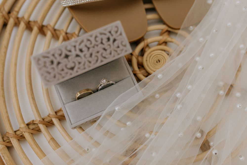 Wedding details featuring a decorated box containing rings with tulle fabric accents.